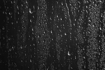Naklejka na ściany i meble Glass with rain drops against dark background