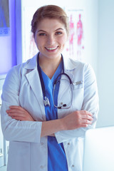 Young woman medic in white uniform standing in clinic's office