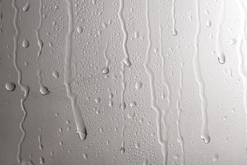 Glass with rain drops against light background