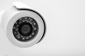 Modern CCTV security camera on white wall. Space for text