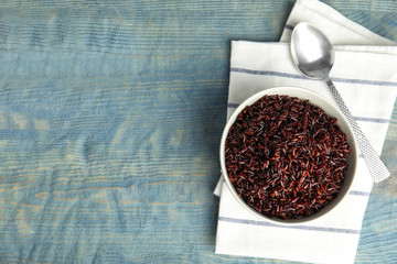 Flat lay composition with delicious cooked brown rice on color wooden table. Space for text