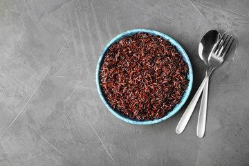 Flat lay composition with delicious cooked brown rice on grey table. Space for text