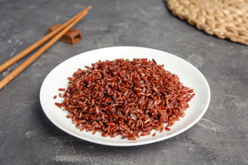 Plate with delicious cooked brown rice on grey table