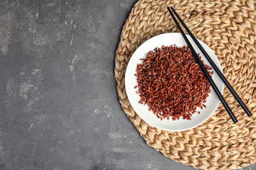 Flat lay composition with delicious cooked brown rice on grey table. Space for text