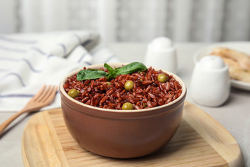 Bowl with delicious cooked brown rice on table indoors