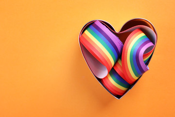 Heart shaped mold and bright rainbow ribbon on color background, top view with space for text....