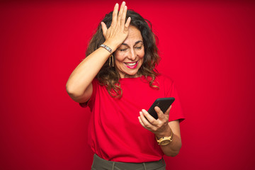 Naklejka premium Middle age senior woman using smartphone over red isolated background stressed with hand on head, shocked with shame and surprise face, angry and frustrated. Fear and upset for mistake.