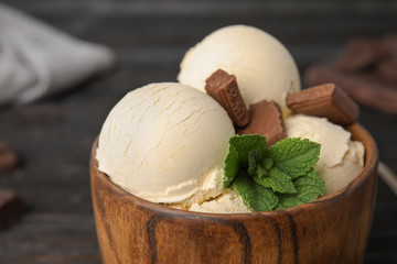 Delicious vanilla ice cream with chocolate and mint in bowl on table, closeup