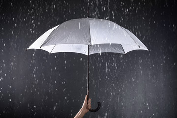 Woman holding white umbrella under rain on dark background, closeup