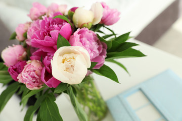 Vase with bouquet of beautiful peonies on table in room, closeup