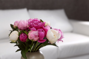 Vase with bouquet of beautiful peonies in room, space for text
