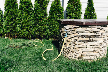 Stone-decorated well in the green backyard of private house