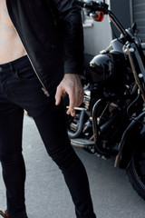 Fototapeta na wymiar cropped view of man with naked torso holding cigarette and standing not far from motorcycle