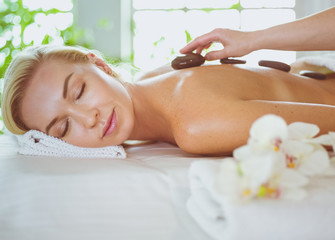 Obraz na płótnie Canvas Young woman in spa salon, getting stones massage