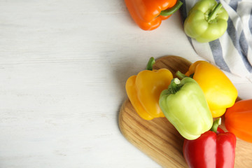 Fresh ripe bell peppers on white wooden table, top view. Space for text