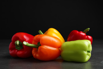 Fresh ripe bell peppers on table against black background