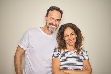 Beautiful middle age couple together standing over isolated white background happy face smiling with crossed arms looking at the camera. Positive person.
