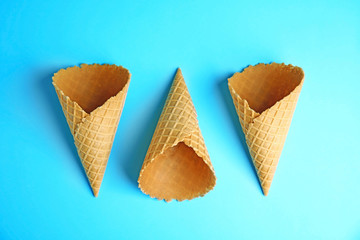 Empty wafer ice cream cones on blue background, flat lay