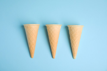 Empty wafer ice cream cones on blue background, flat lay