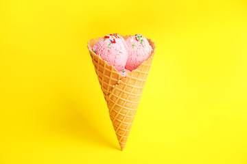 Delicious ice cream in wafer cone on yellow background