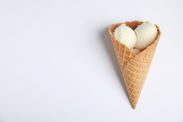 Delicious vanilla ice cream in wafer cone on white background, top view