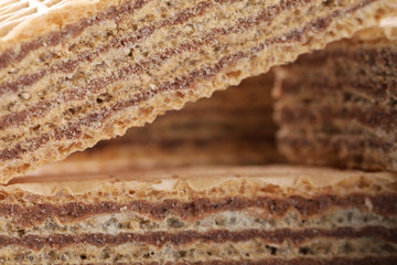 Delicious crispy wafers with chocolate filling as background, closeup