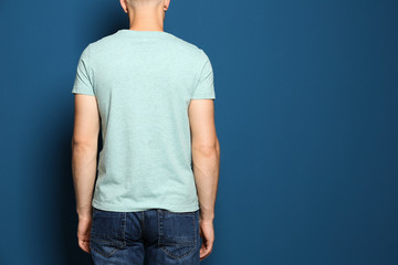 Back view of young man wearing blank t-shirt on blue background, closeup. Mockup for design