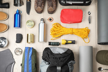 Flat lay composition with different camping equipment on wooden background