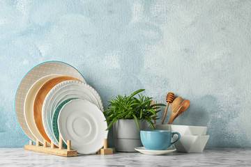 Green plant and different kitchenware on table near color wall. Modern interior design