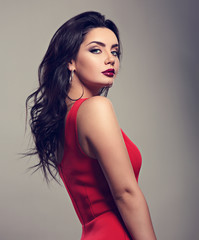 Beautiful bright makeup woman with long black curly hair style in red dress, burgundy lipstick with...