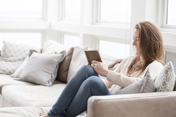 Happy woman reading a book while sitting on couch