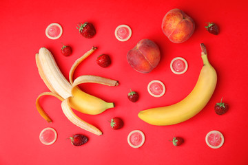 Flat lay composition with condoms and exotic fruits on red background. Erotic concept