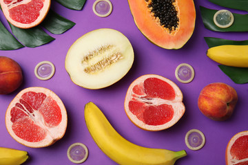 Flat lay composition with condoms and exotic fruits on purple background. Erotic concept