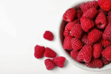 Top view of bowl with delicious ripe raspberries on white background, closeup
