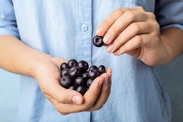 Female holding fresh acai berries, closeup view