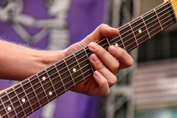 Hands and fingers playing eletric guitar during a band's performance at a rock concert