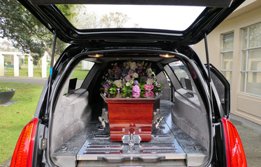closeup shot of a funeral casket in a hearse or chapel or burial at cemetery