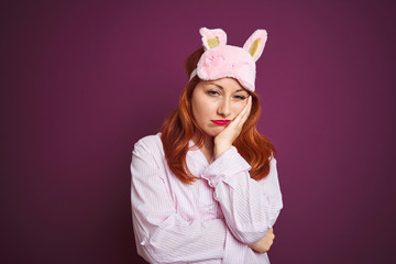 Obraz na płótnie Canvas Young beautiful redhead woman wearing pajama and mask over purple isolated background thinking looking tired and bored with depression problems with crossed arms.