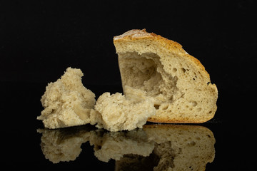 Pinched off slice of fresh baked rye wheat bread with three pieces isolated on black glass