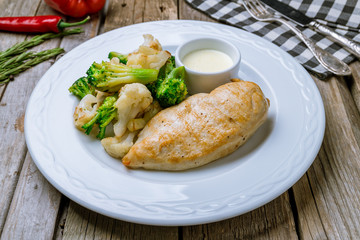 Fried chicken breast with broccoli on wooden table