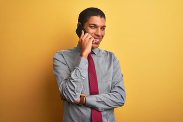 Young handsome arab businessman talking on smartphone over isolated yellow background with a happy face standing and smiling with a confident smile showing teeth