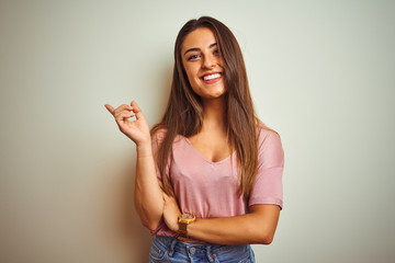 Young beautiful woman wearing casual t-shirt standing over isolated white background with a big smile on face, pointing with hand and finger to the side looking at the camera.