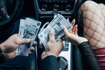 cropped view of client paying money to prostitute in car - obrazy, fototapety, plakaty