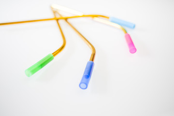 Bent stainless steel metal multicolor reusable straws with a blue, pink and green silicone straw tips on a white background.