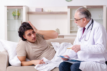 Old male doctor visiting young male patient