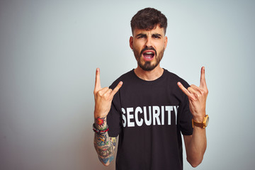 Young safeguard man with tattoo wering security uniform over isolated white background shouting...