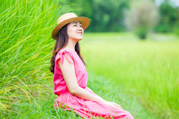 Portrait of beautiful Asian woman in vintage pink dress enjoying in the rice field.