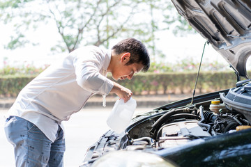 Man refill water into car's cooler system tank close up.