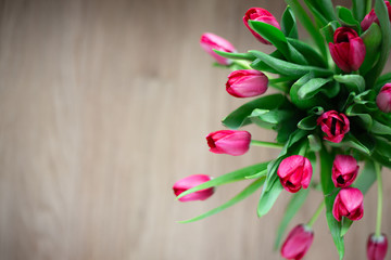 Bouquet of pink tulips on a brown wooden background