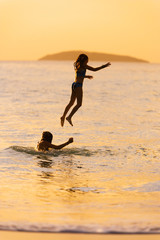 Fototapeta na wymiar Younger girl jumping off of an older girls shoulder while swimming in Cinnamon Bay, St. John, USVI
